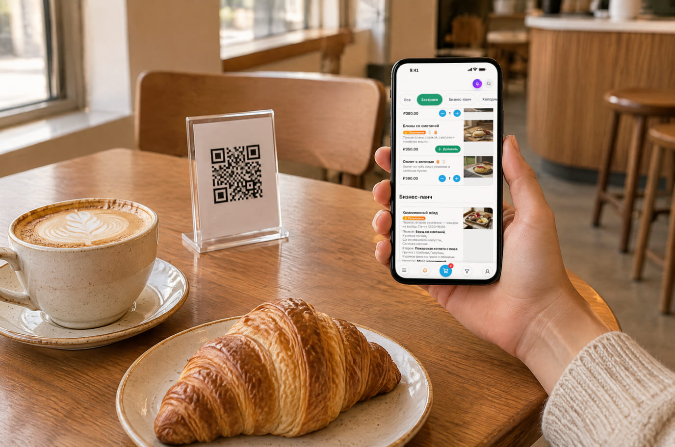 Гость кафе открыл меню с блюдами и ценами на телефоне рядом с QR-карточкой на столе